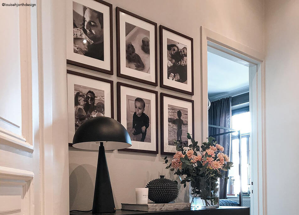 Fotogalerija v hodniku, črno-bele fotografije v temnih lesenih okvirjih